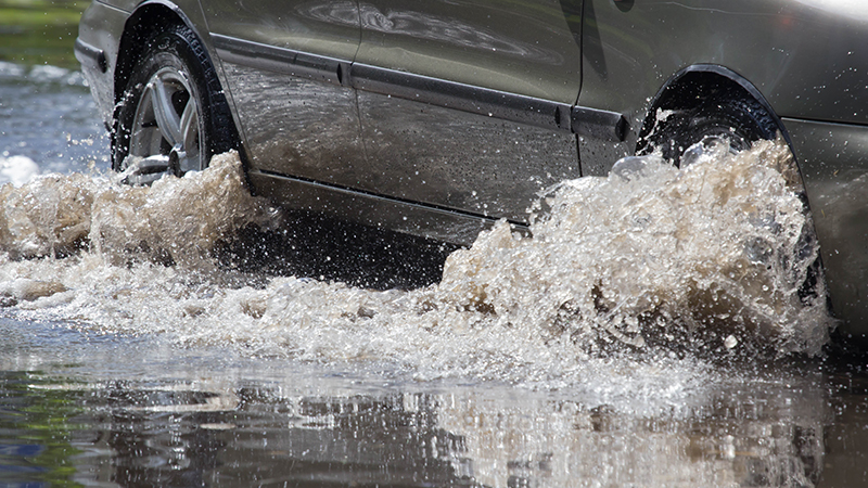 cars driving on a flooded road during a flood caused by heavy rain