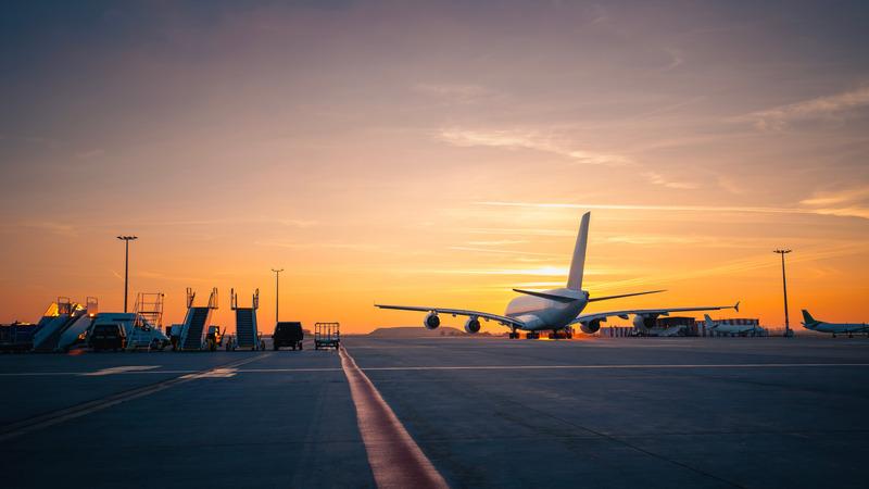 Airplane on runway with sunset in the background.