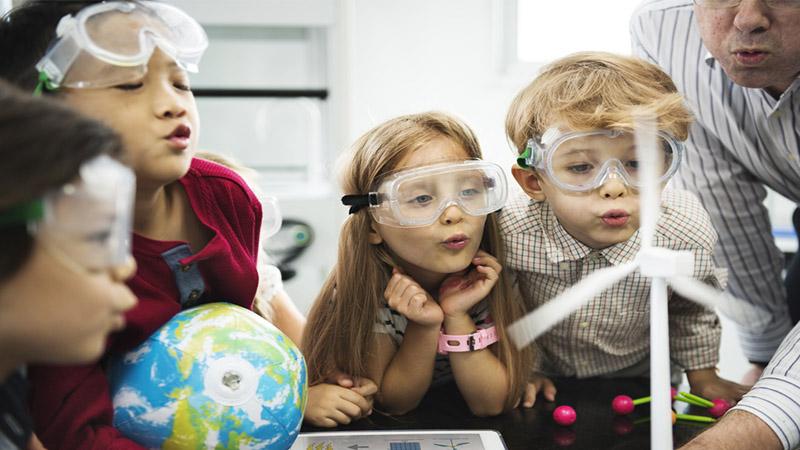 Diverse kindergarten students learning energy producer from solar windmill in science class