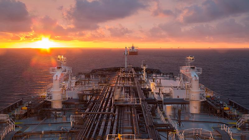 Oil tanker sailing towards a sunset