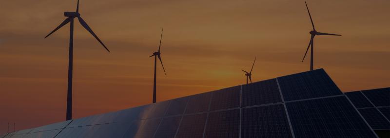 Windmills and solar panels at dusk