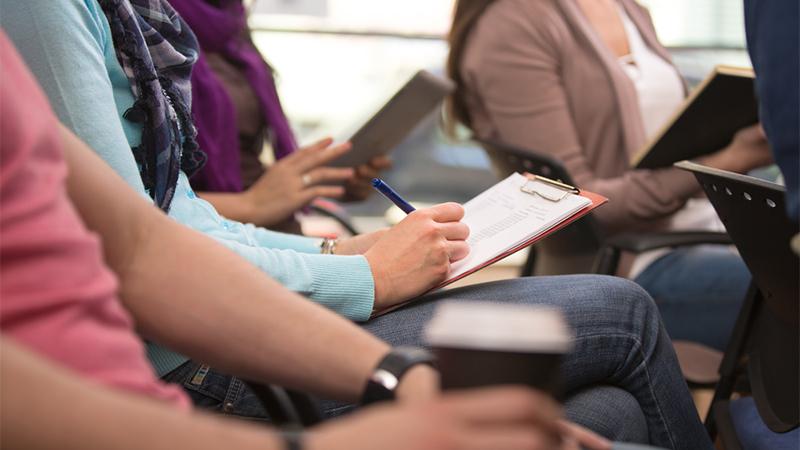 People listening and taking notes at a seminar